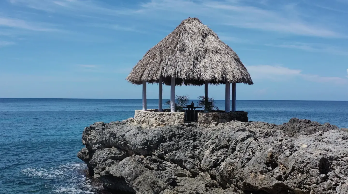 A thatched pavilion sits on a rocky point above the sea at Tensing Pen Hotel.