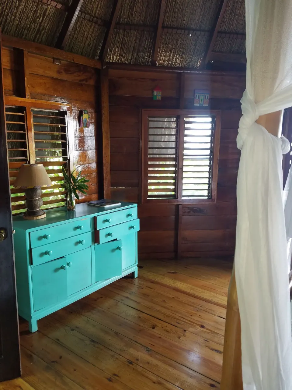 Turquoise dresser and louvered windows in a wood guest room at Tensing Pen Hotel.