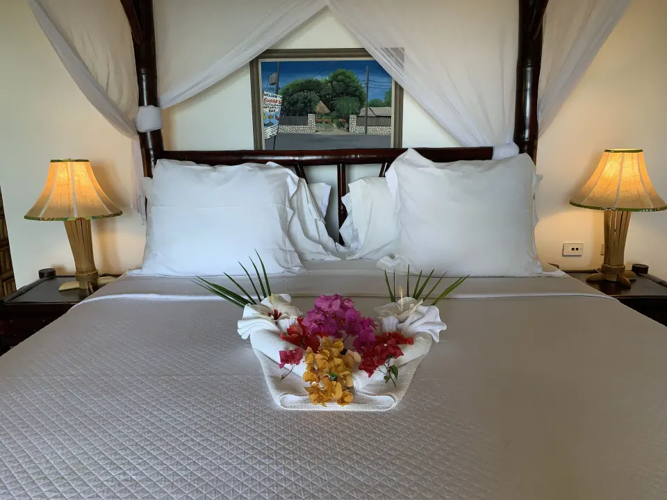 Deluxe Room Ocean View bed with floral towel arrangement at Tensing Pen Hotel.