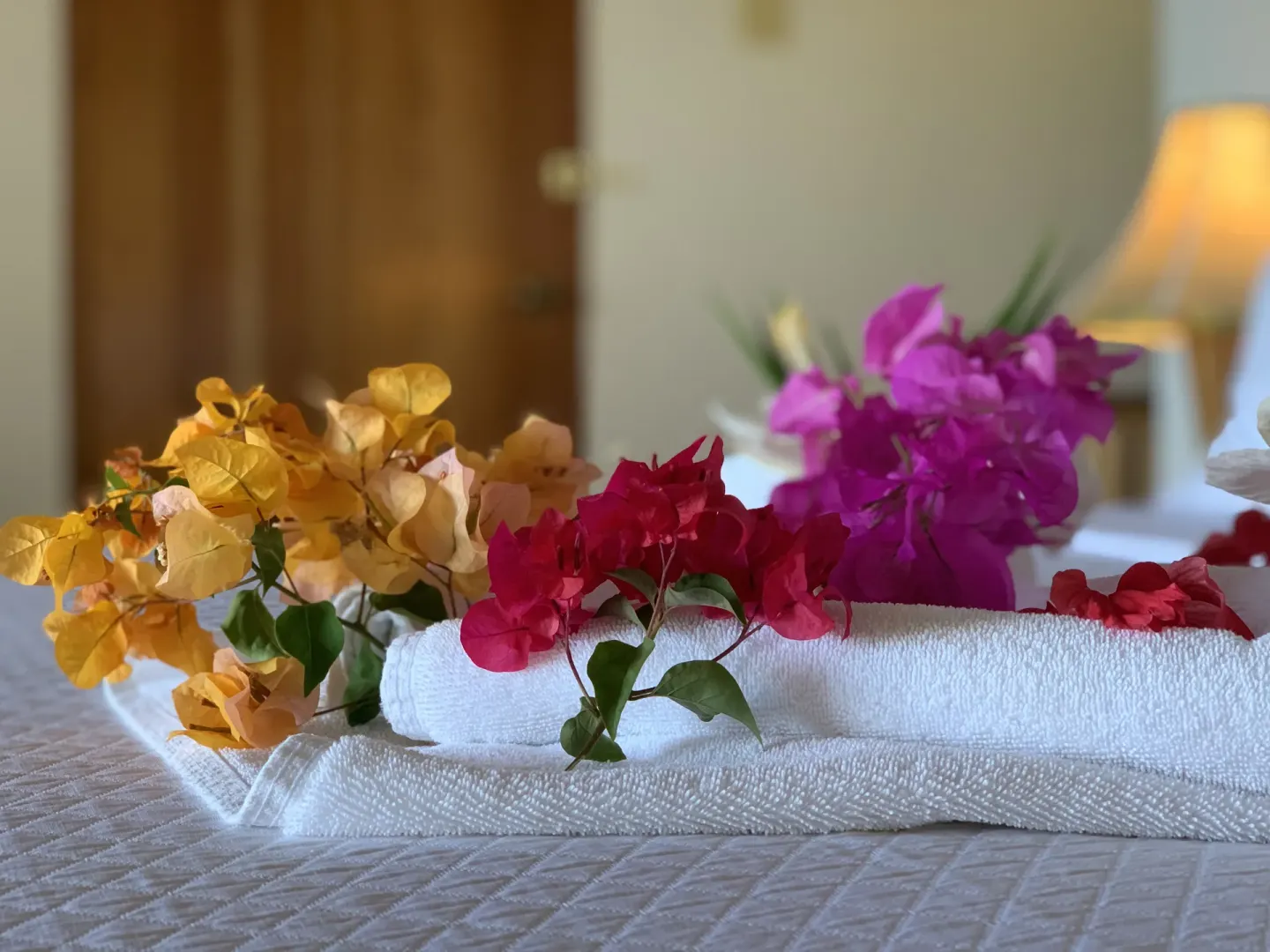 Folded towels and tropical flowers on a Deluxe Room bed at Tensing Pen Hotel.