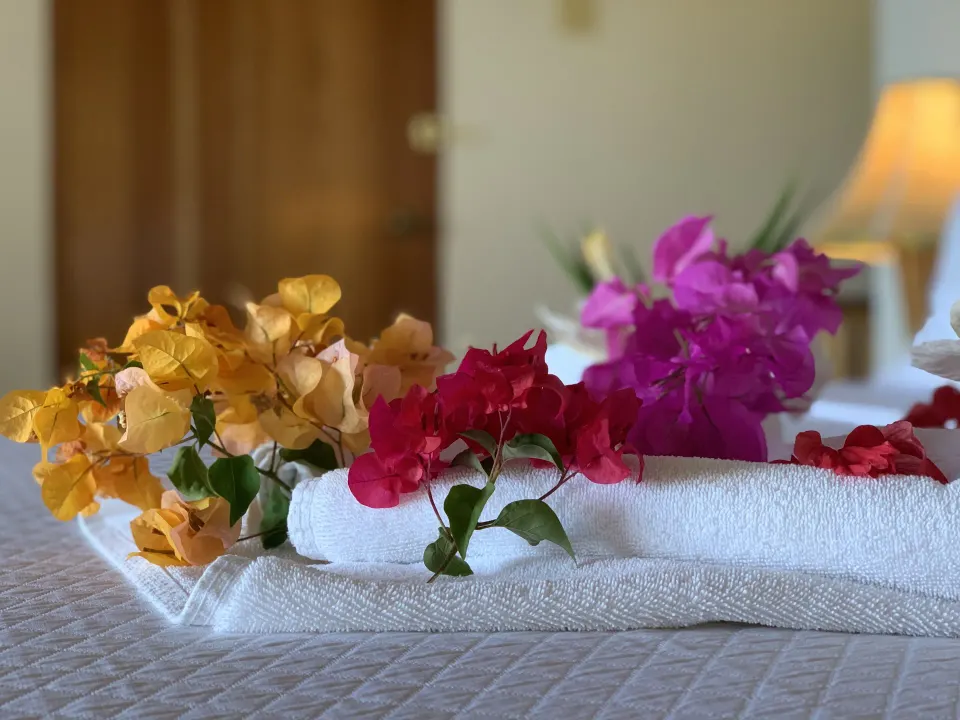 Folded towels and tropical flowers on a Deluxe Room bed at Tensing Pen Hotel.