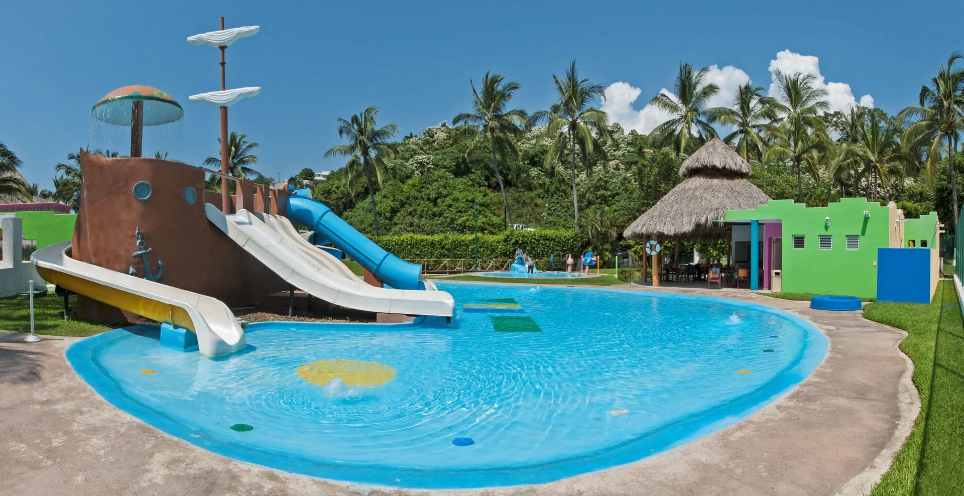 Children's pool with ship-themed slides and palm trees at Tesoro Manzanillo.