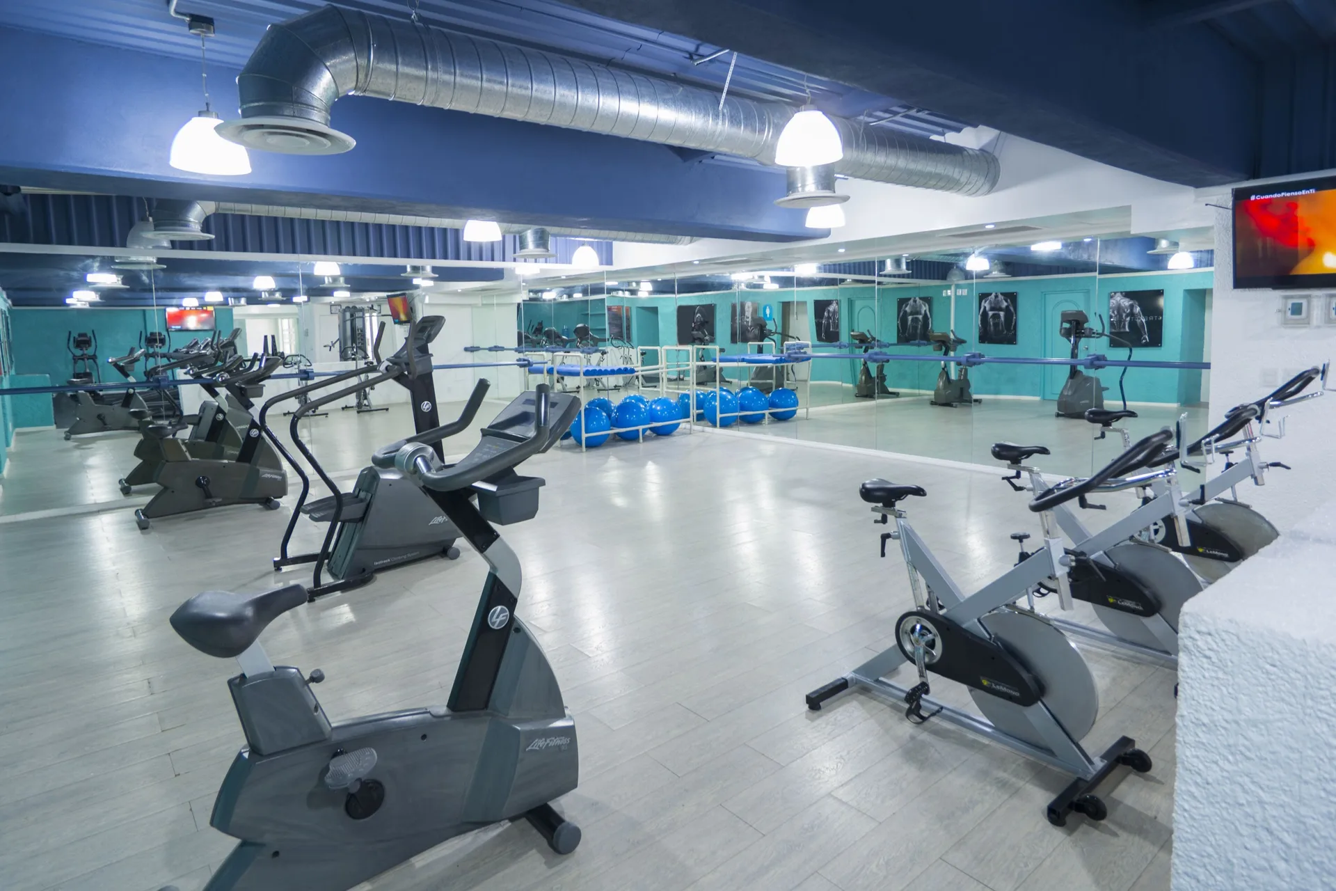 Spacious fitness studio with bikes, exercise balls, mirrors, and teal walls at Tesoro Manzanillo.
