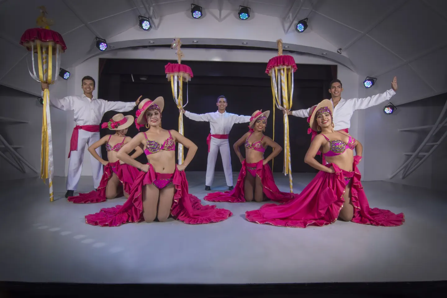 Stage performers in pink costumes pose with tall props at Tesoro Manzanillo.