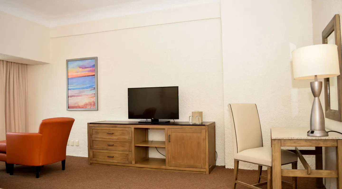Junior Room TV cabinet, desk chair, lamp, and orange chair at Tesoro Manzanillo.