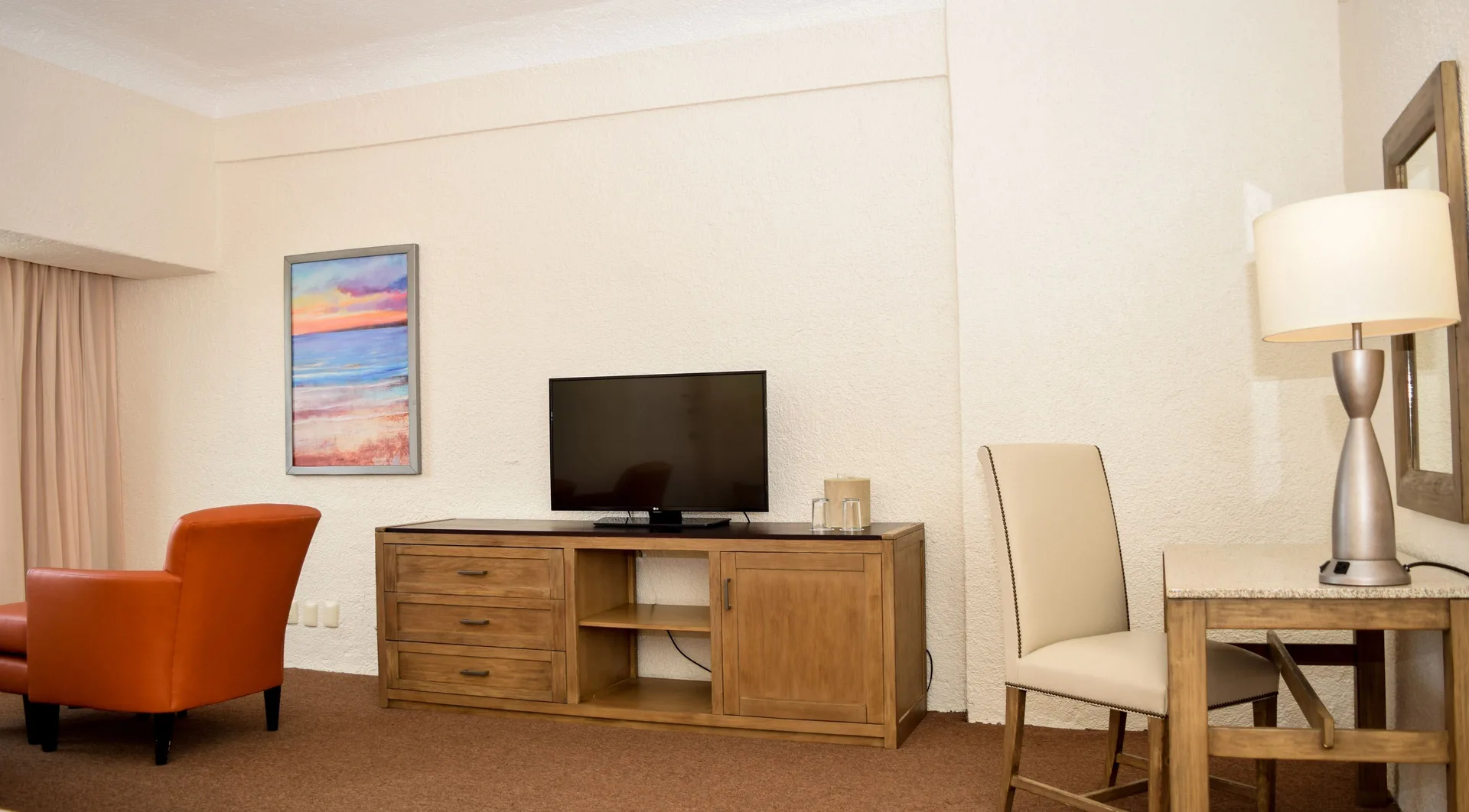 Junior Room TV cabinet, desk chair, lamp, and orange chair at Tesoro Manzanillo.