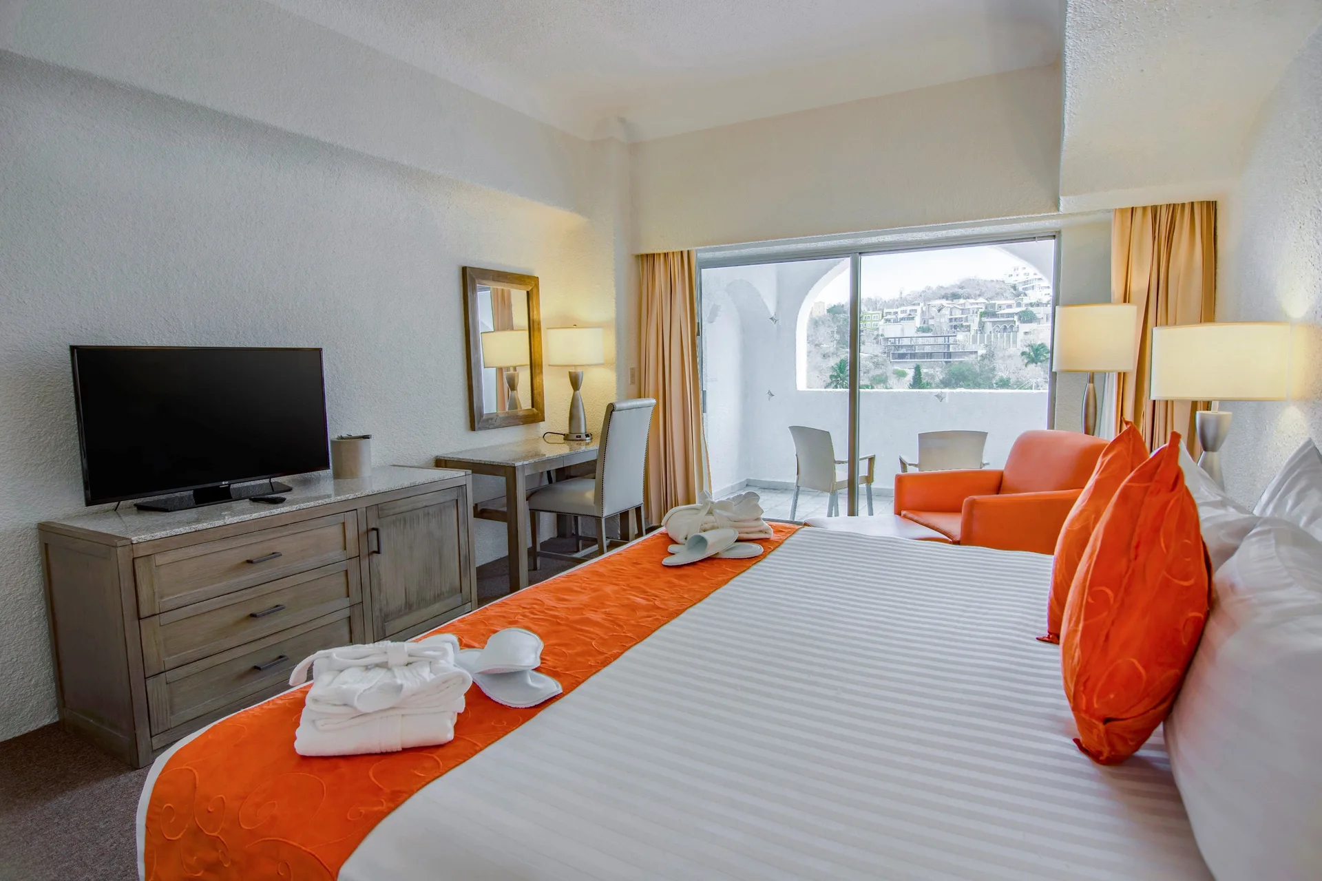 Master Suite king bed with orange accents and balcony seating at Tesoro Manzanillo.