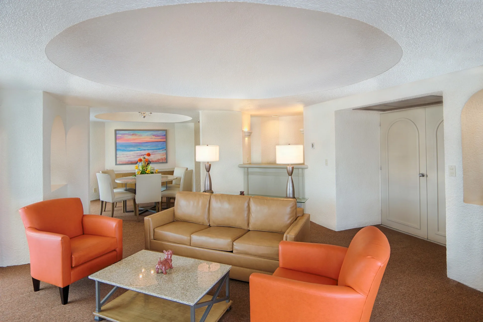 Master Suite living room with sofa, orange chairs, and dining area at Tesoro Manzanillo.