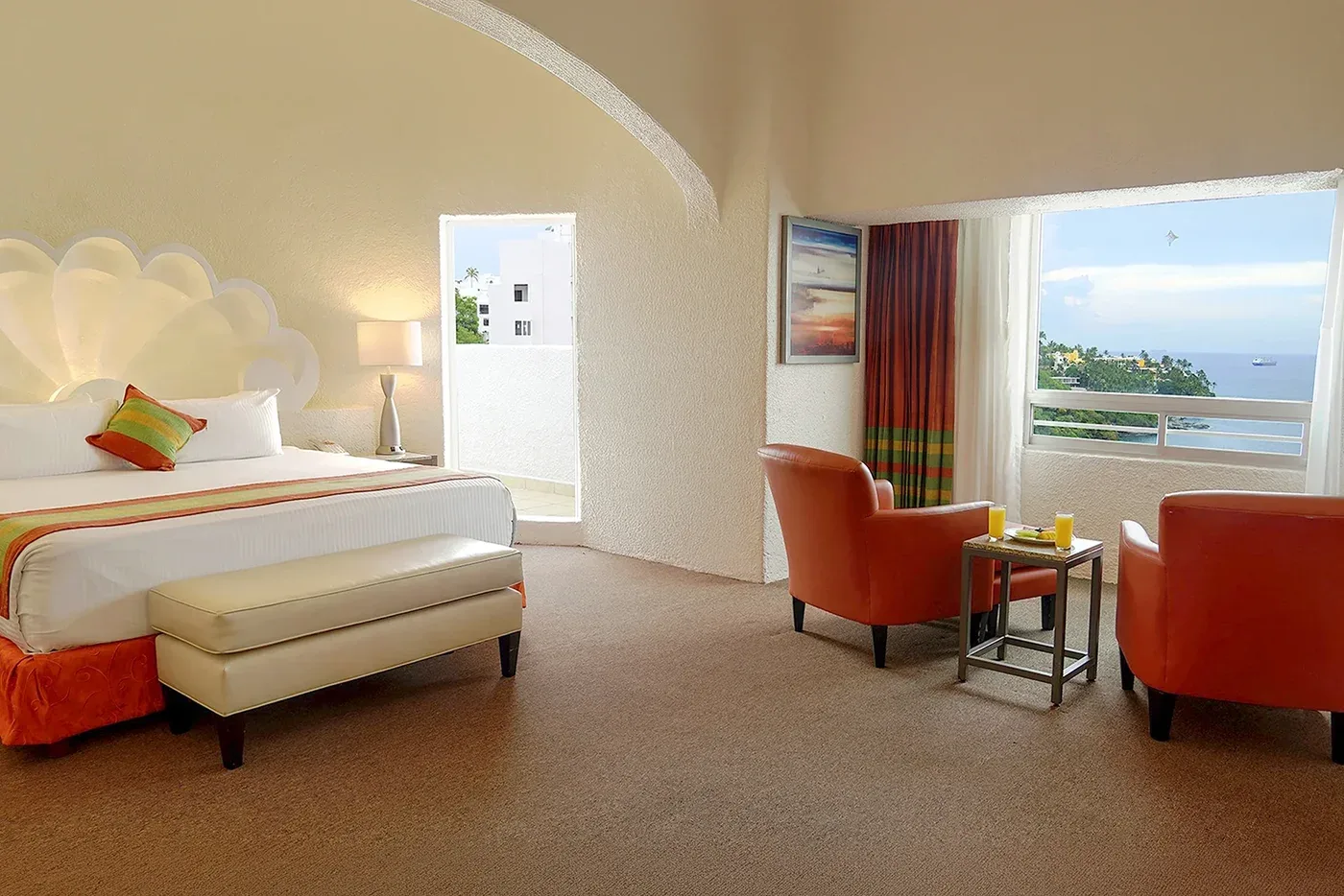 Sea View room with king bed, armchairs, and ocean-facing window at Tesoro Manzanillo.