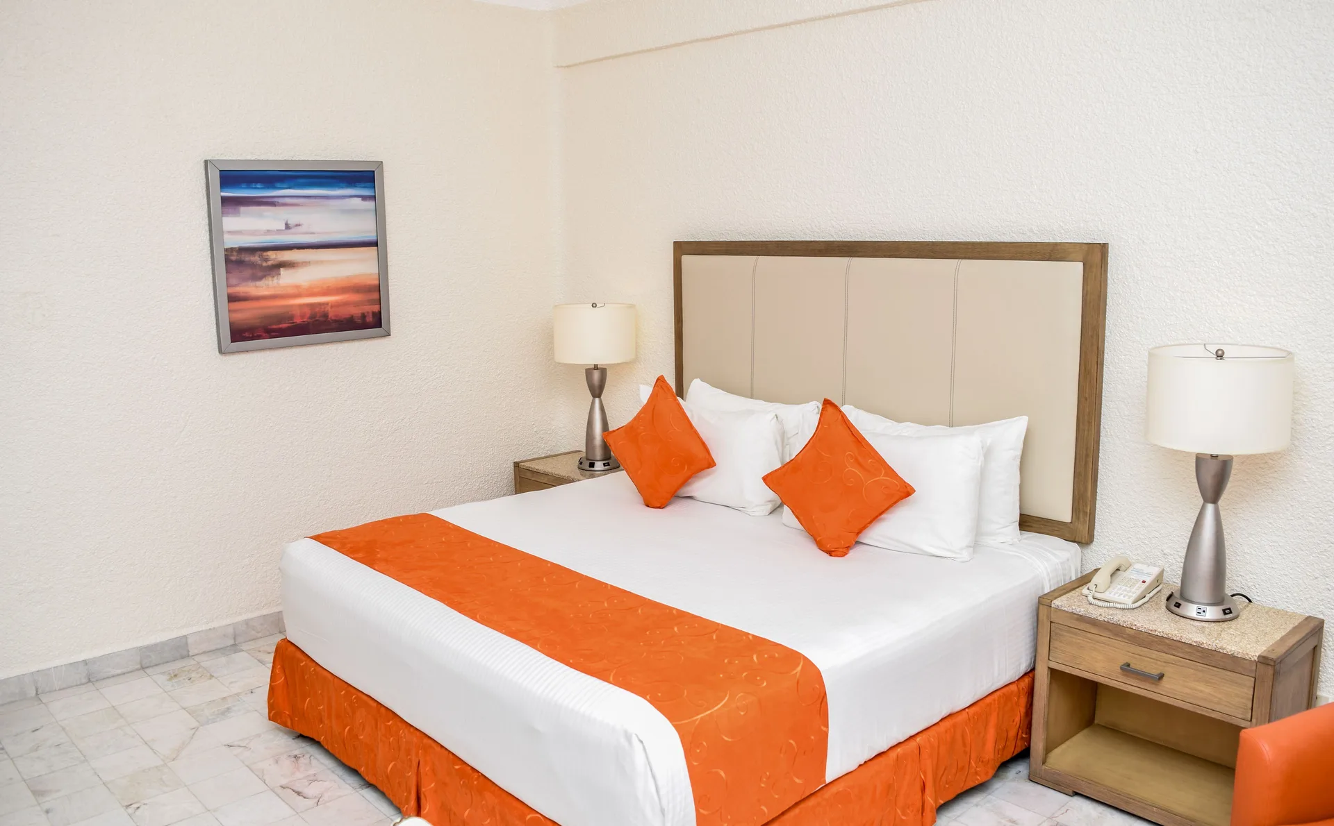 Standard Room Mountain View king bed with orange accents and bedside tables at Tesoro Manzanillo.
