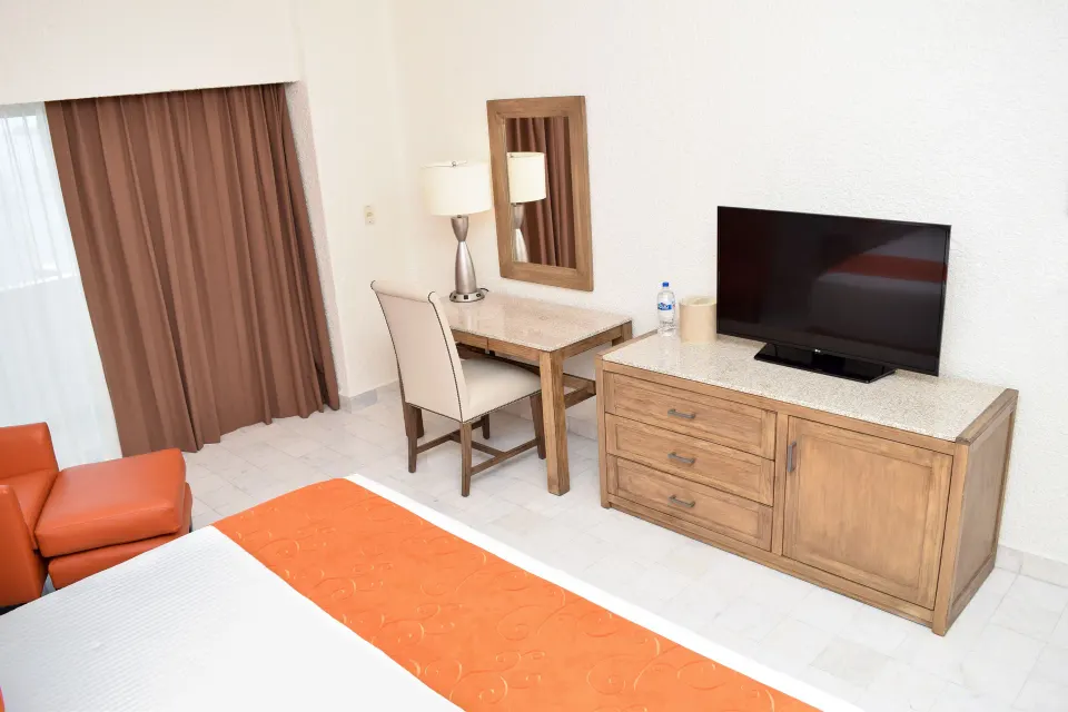 Standard Room Mountain View desk, TV, curtains, and bed corner at Tesoro Manzanillo.