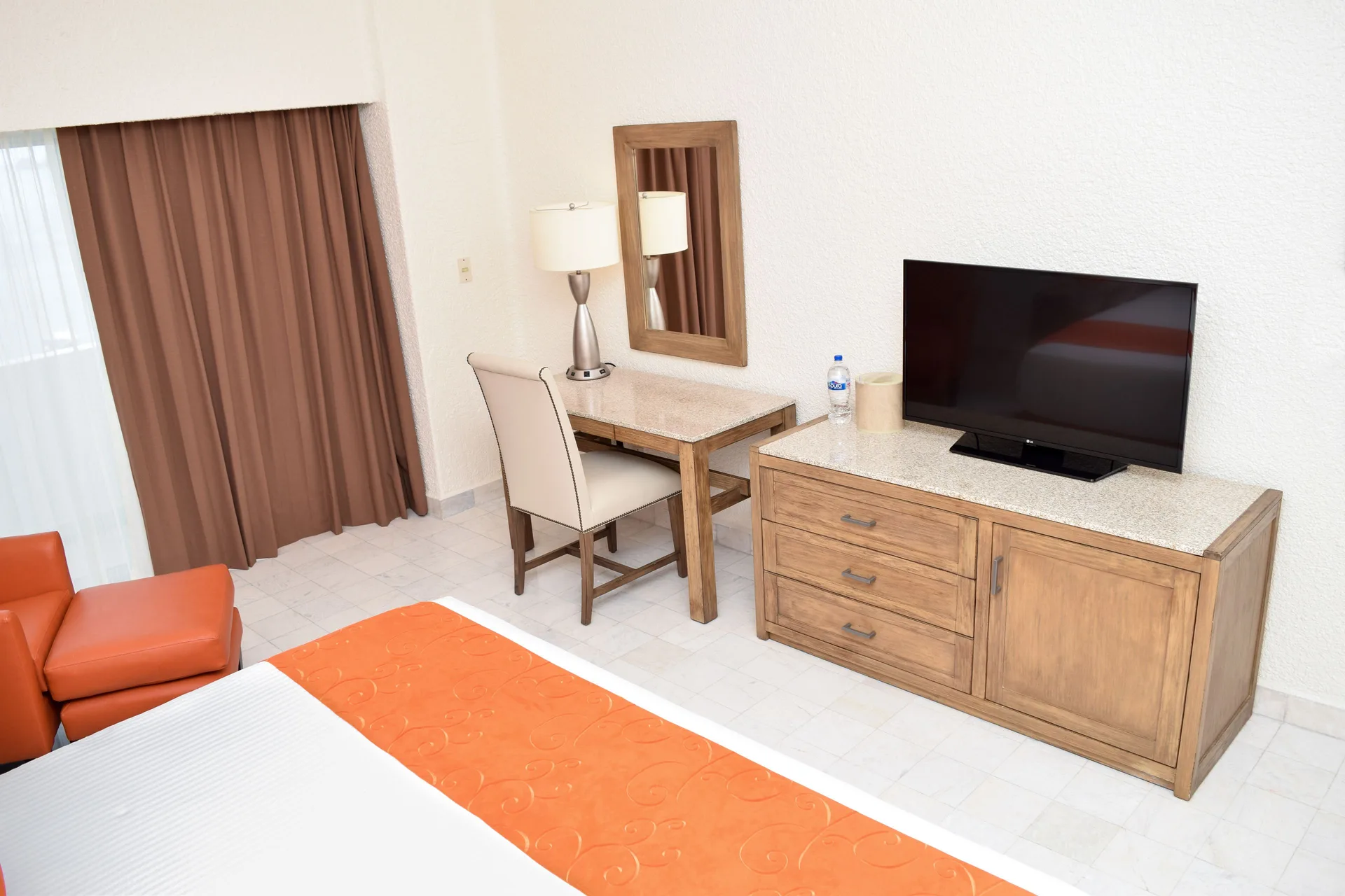 Standard Room Mountain View desk, TV, curtains, and bed corner at Tesoro Manzanillo.