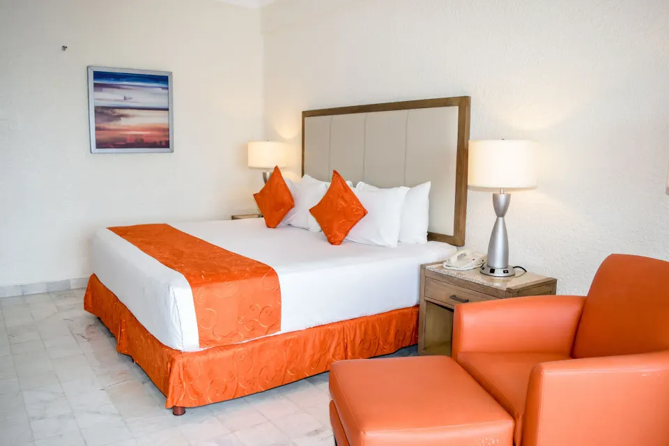 Standard Room Mountain View king bed and orange chair at Tesoro Manzanillo.