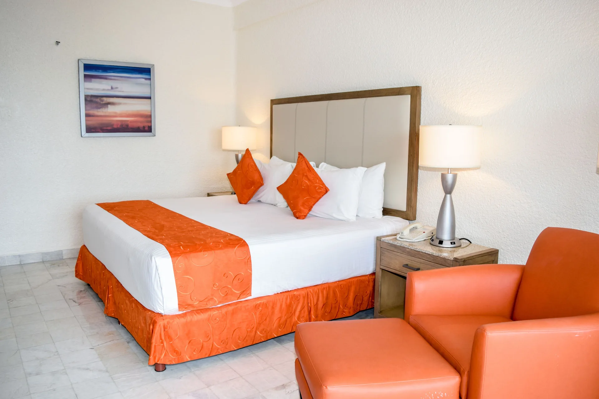 Standard Room Mountain View king bed and orange chair at Tesoro Manzanillo.