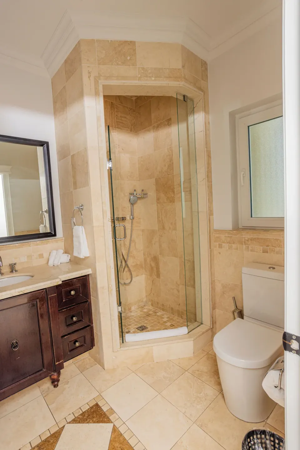 Bathroom with glass shower, vanity, and toilet at The Atrium Resort.
