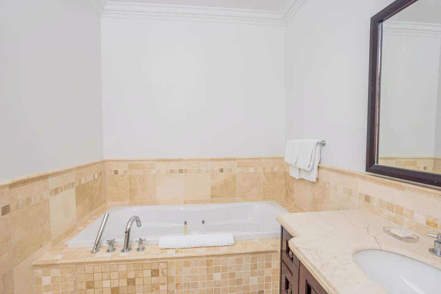 Bathroom soaking tub and vanity with beige tile at The Atrium Resort.