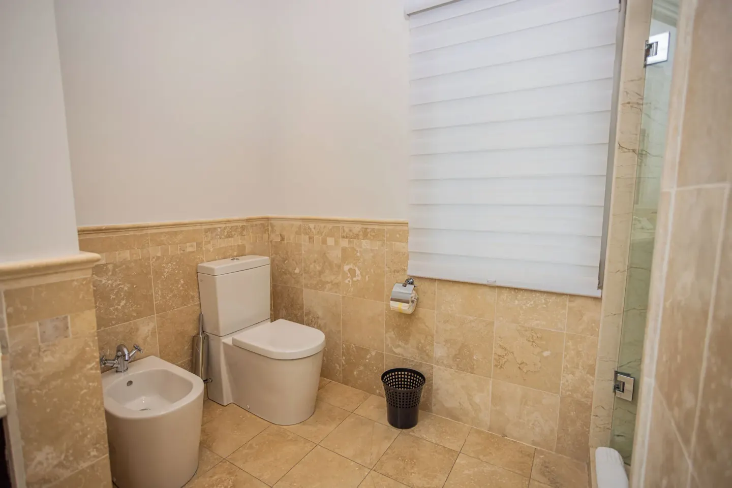 Bathroom with toilet, bidet, window shade, and glass shower at The Atrium Resort.