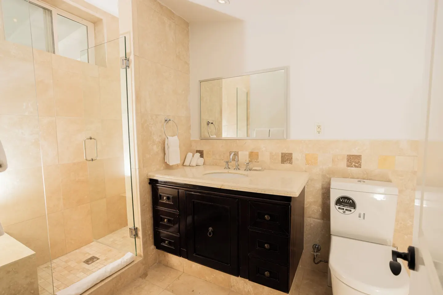Bathroom vanity, toilet, and glass shower at The Atrium Resort.