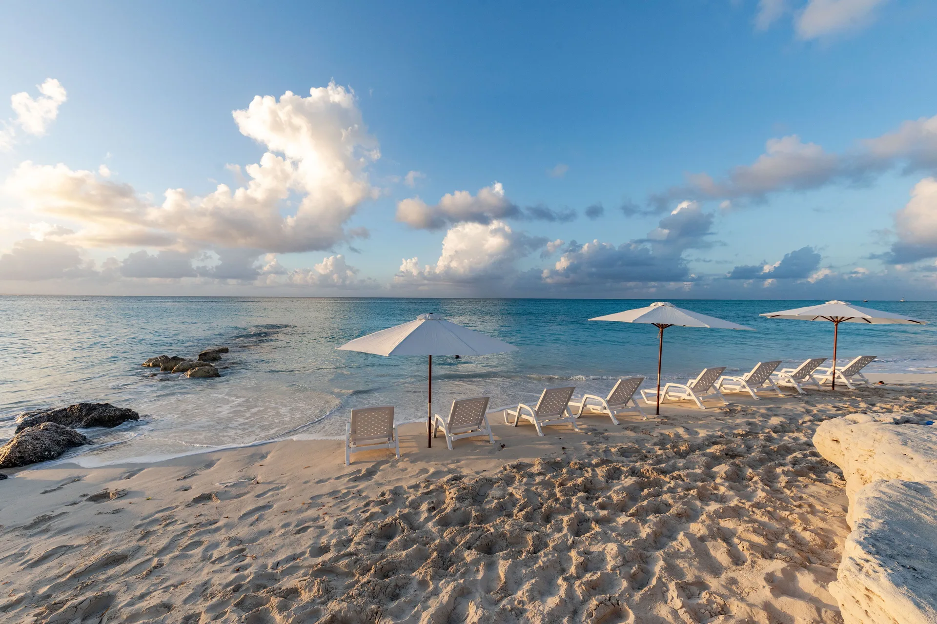 Beach loungers and umbrellas beside calm blue water near The Atrium Resort.
