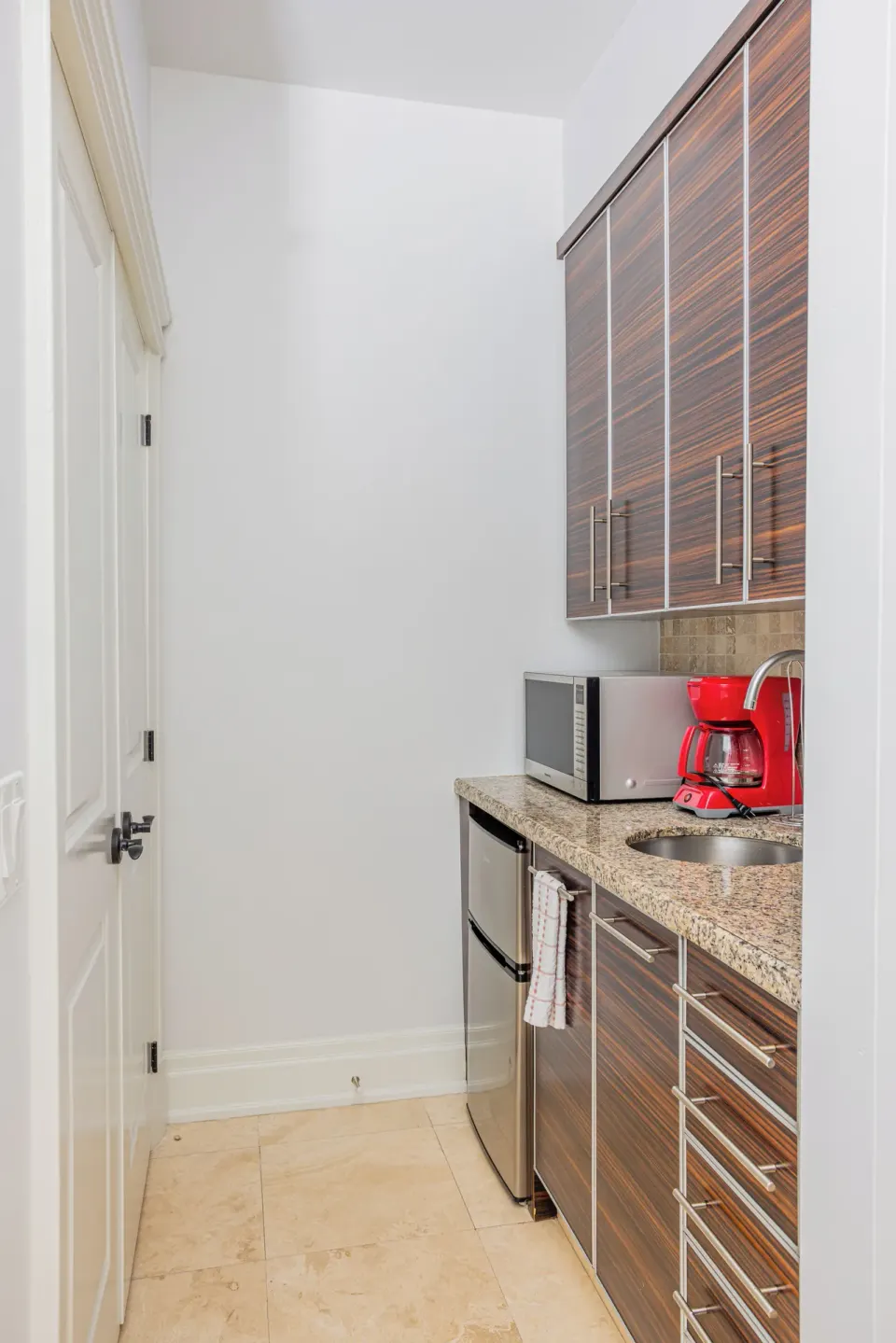 Compact kitchenette with sink, mini fridge, microwave, and red coffee maker at The Atrium Resort.