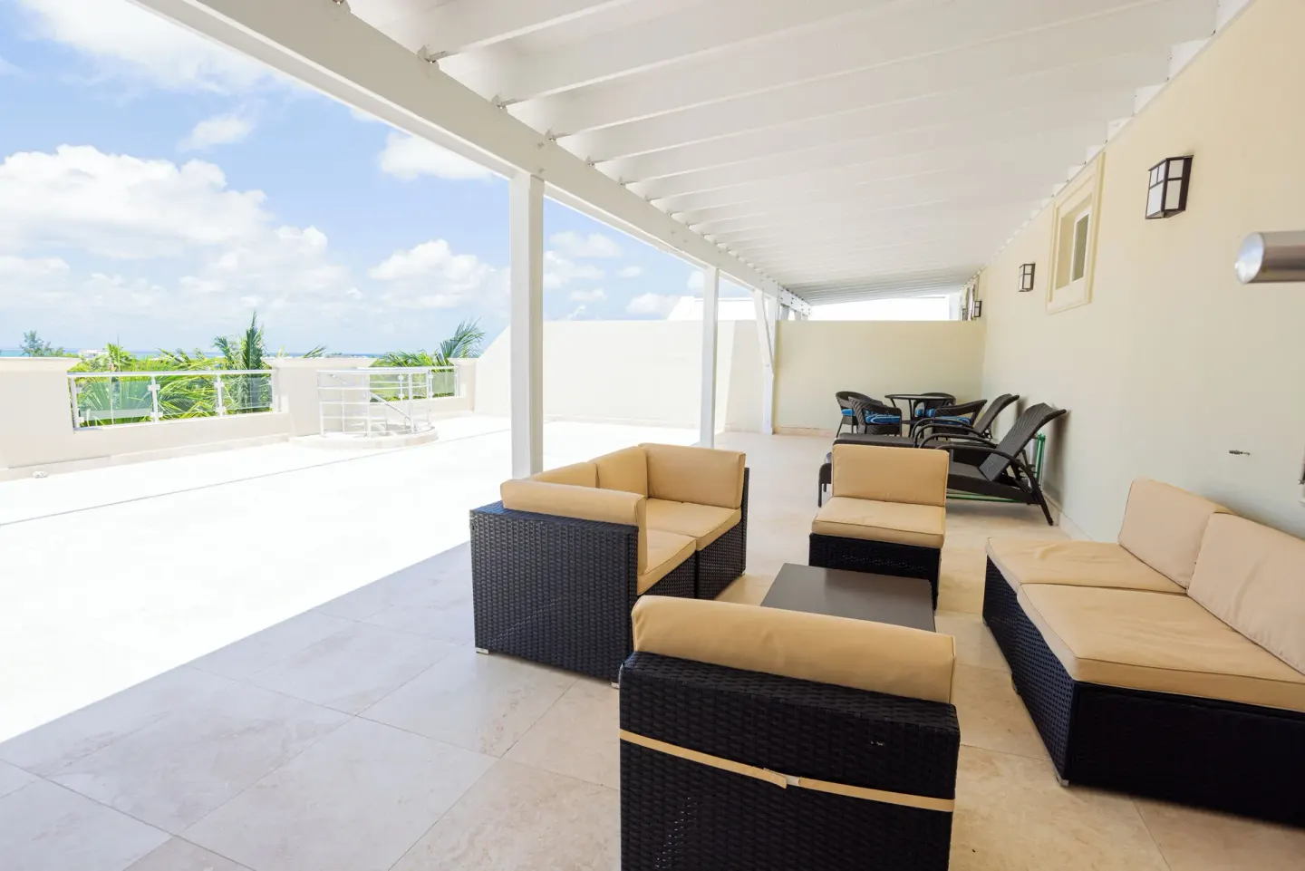 Covered terrace with cushioned wicker seating and distant water views at The Atrium Resort.