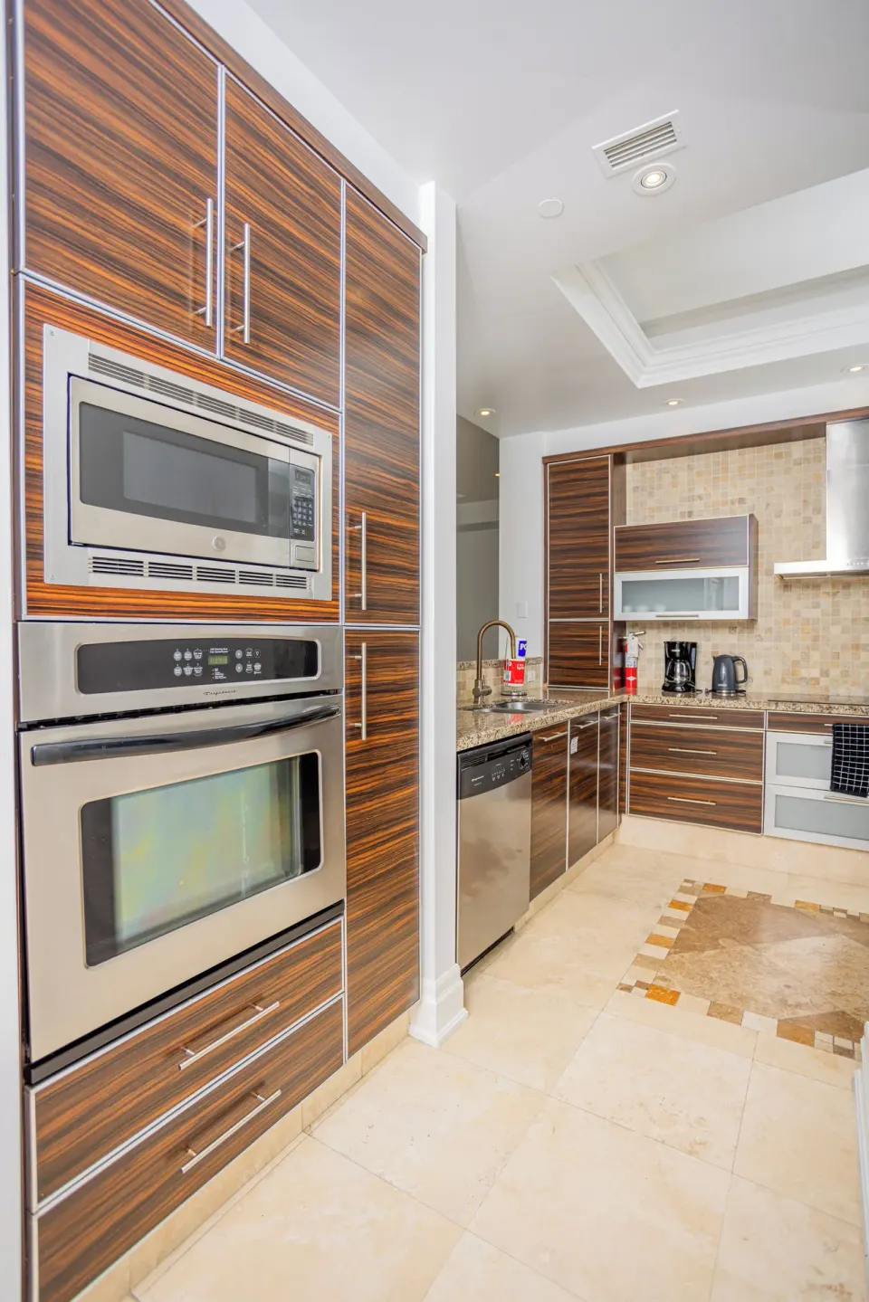 Kitchen with wood cabinetry, oven, microwave and counters at The Atrium Resort.