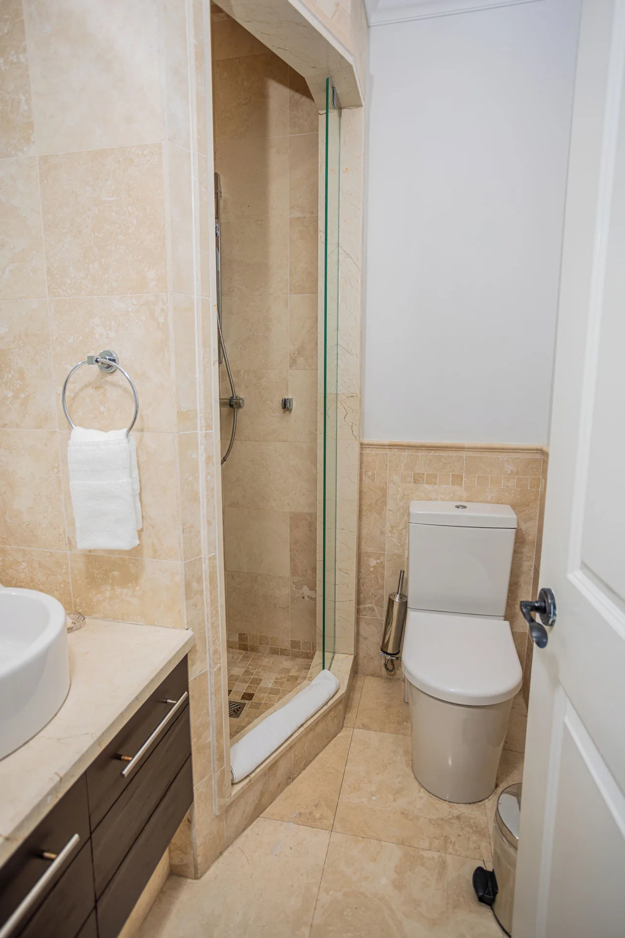 Bathroom with glass shower, vanity and toilet at The Atrium Resort.