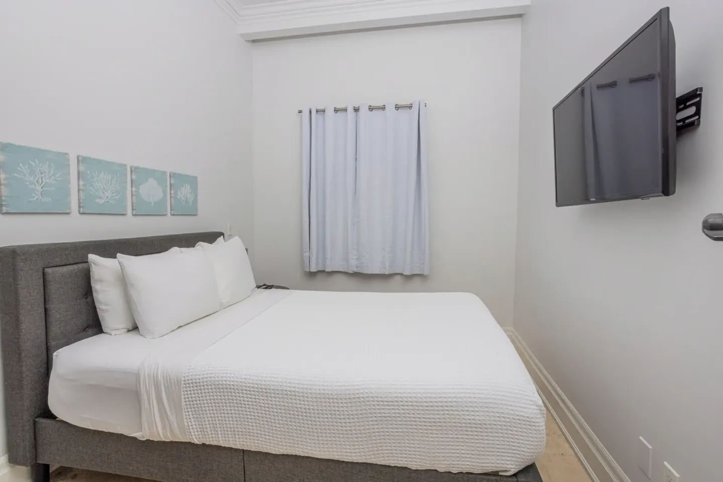 Guest bedroom with white bedding and wall-mounted TV at The Atrium Resort.