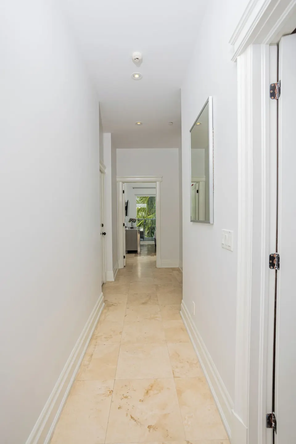 Bright white guest room hallway with tile floor at The Atrium Resort.