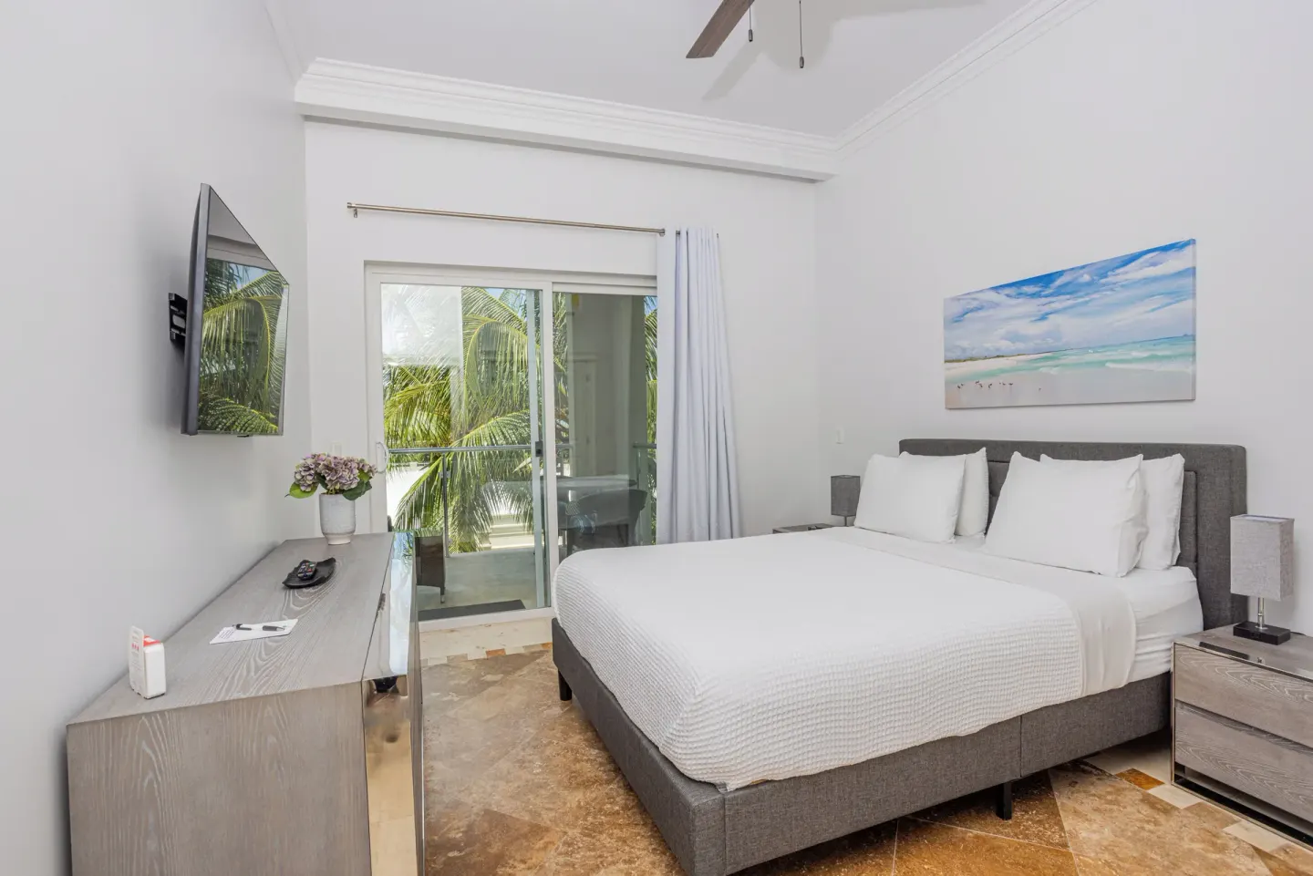 Guest room with king bed, balcony doors, TV, and palm views at The Atrium Resort.