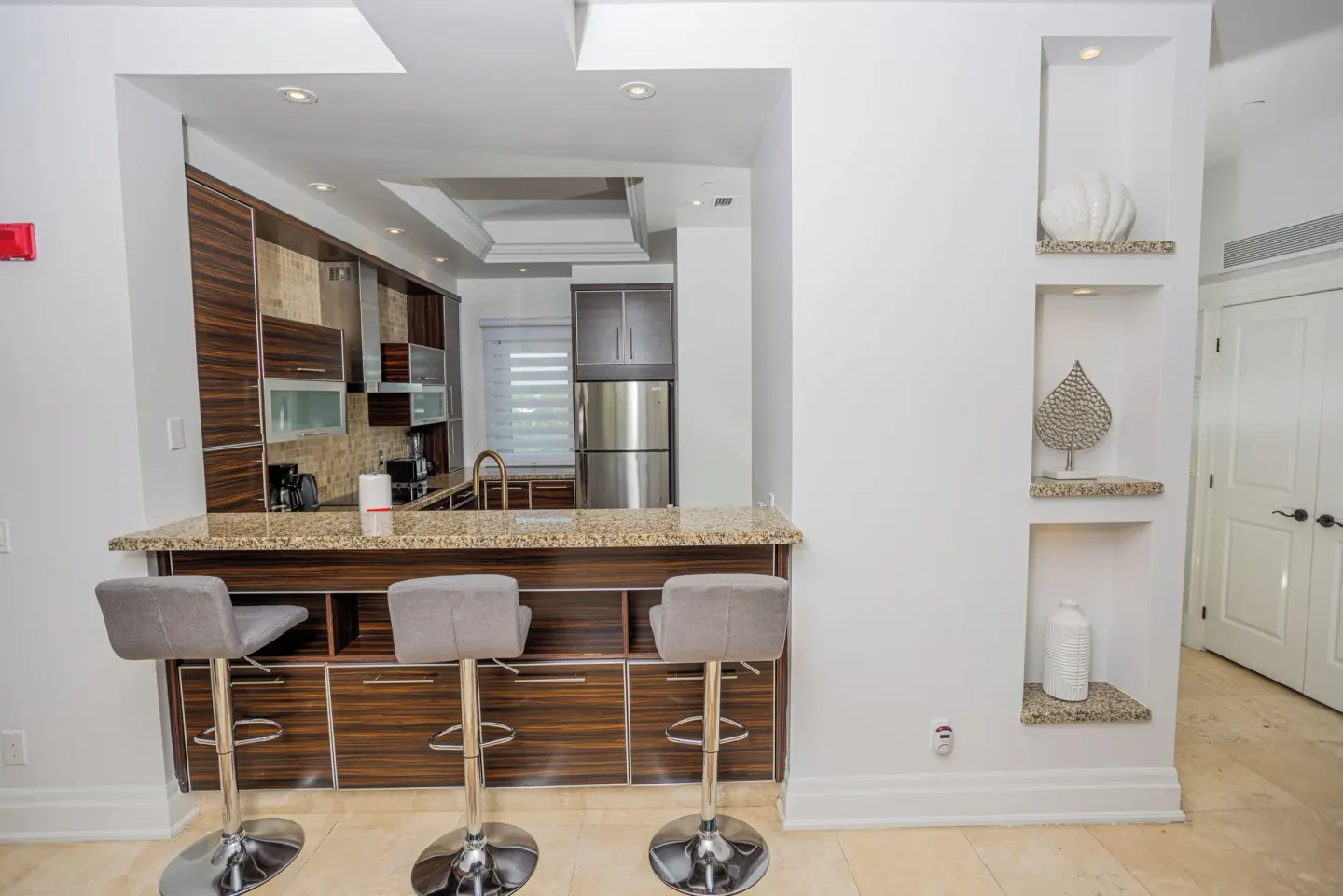 Kitchen bar with three stools and display shelves at The Atrium Resort.