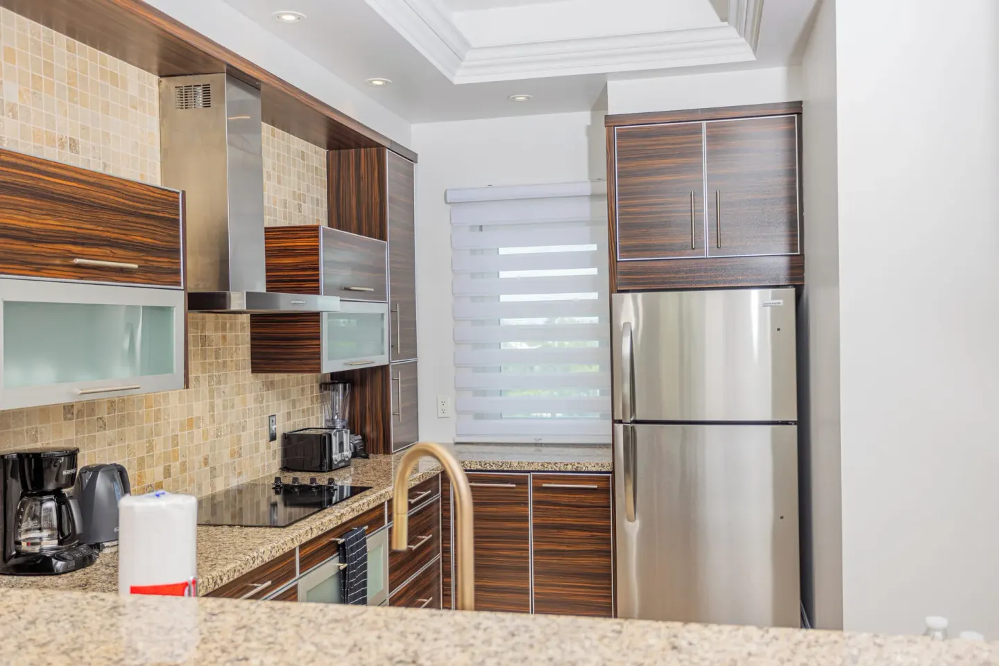 Kitchen with refrigerator, coffee maker and tiled backsplash at The Atrium Resort.