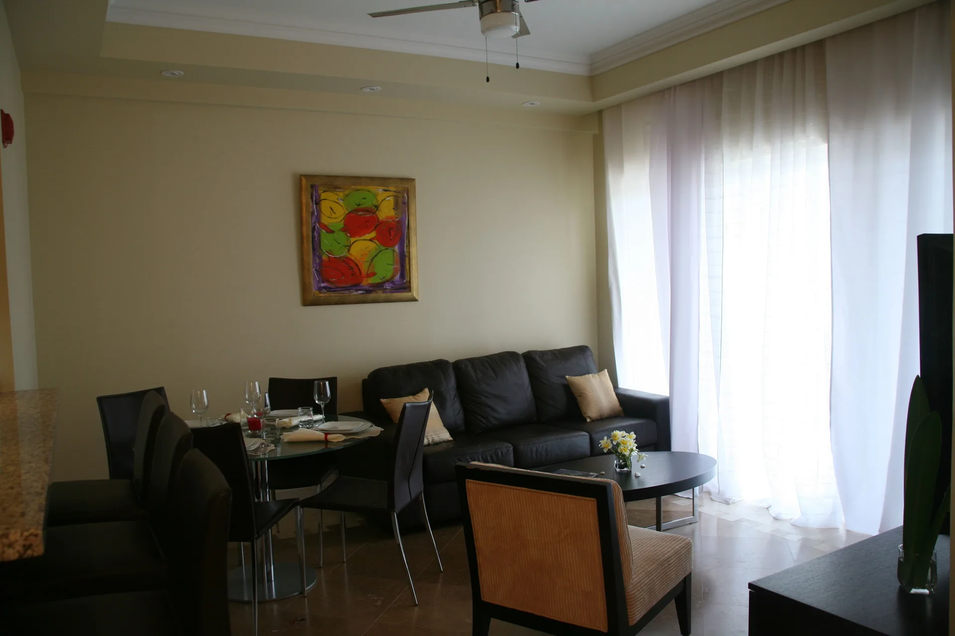 Living and dining area with sofa, table setting, coffee table, and sheer curtains at The Atrium Resort.