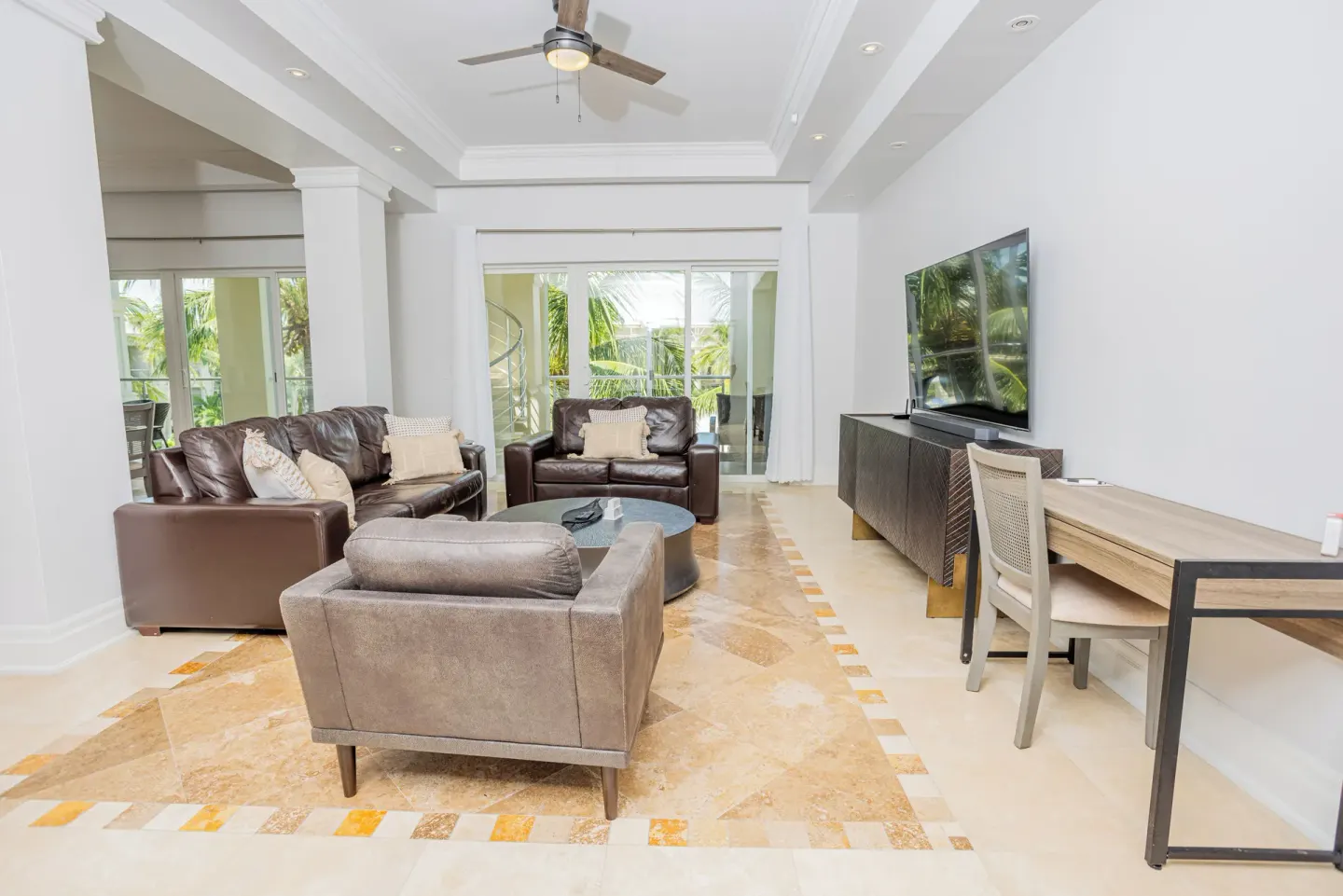 Living room with leather sofas, TV and balcony doors at The Atrium Resort.