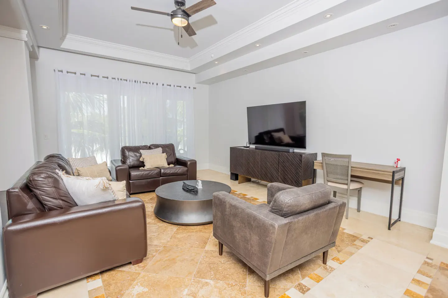 Living room seating area with TV and desk at The Atrium Resort.