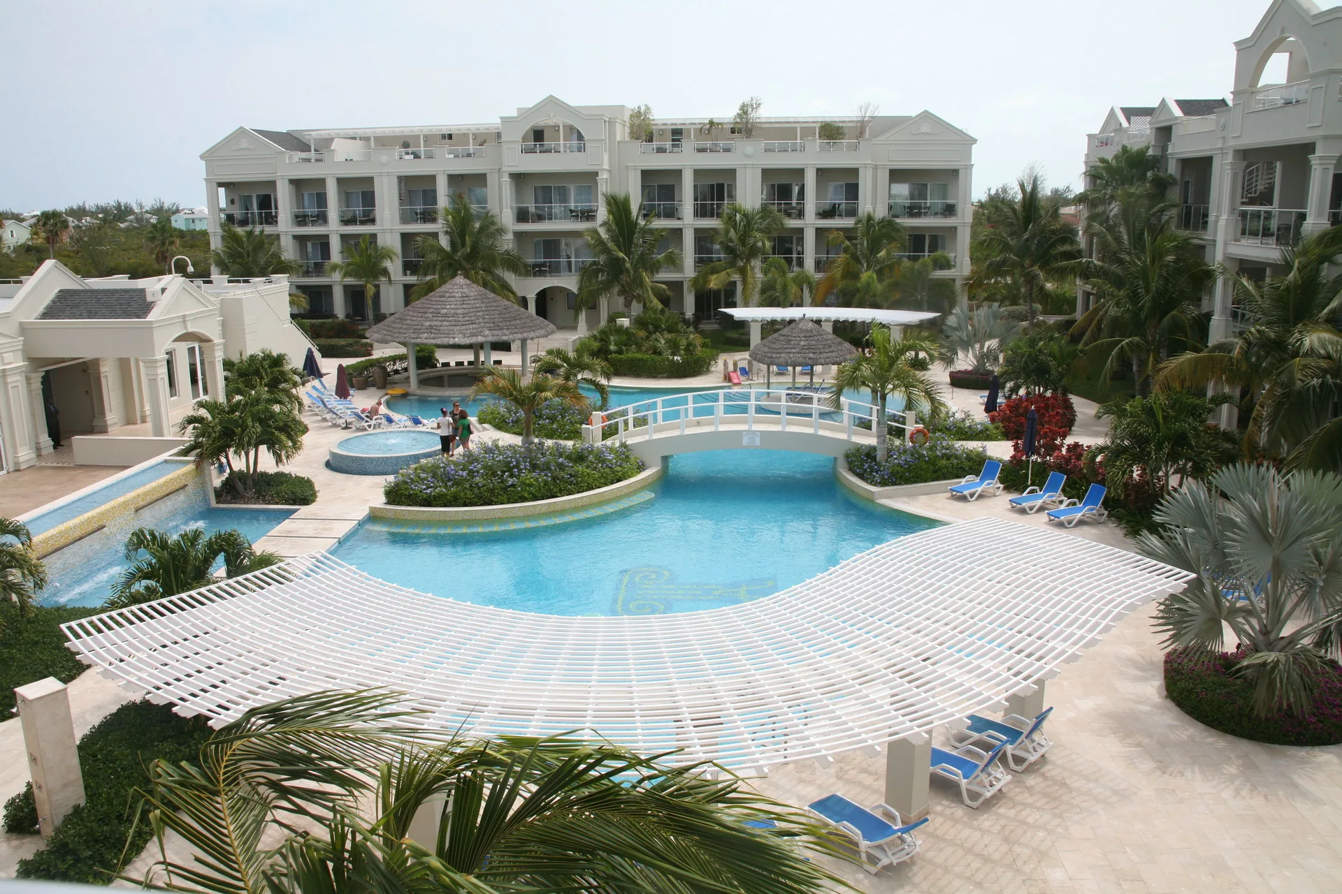 Pool courtyard with palms, bridge, loungers, and resort buildings at The Atrium Resort.