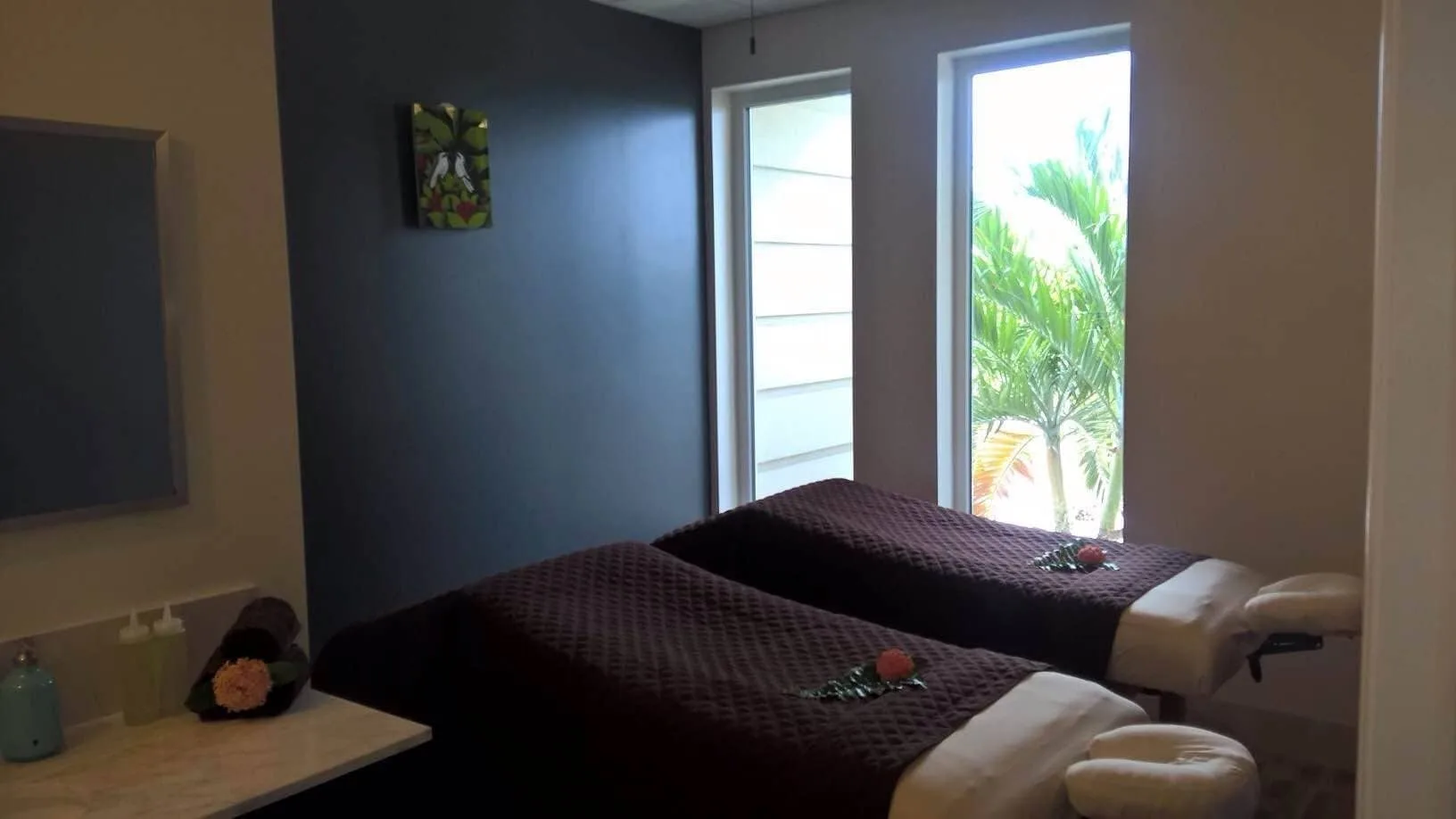 A spa treatment room with two massage tables and tall windows at The Atrium Resort.