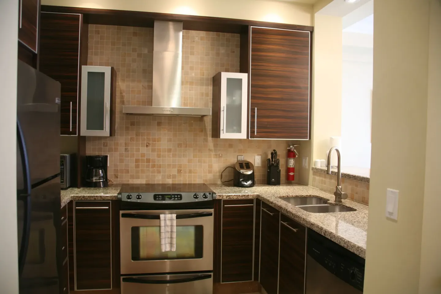Kitchen with stainless range, sink, granite counters, and dark cabinets at The Atrium Resort penthouse.