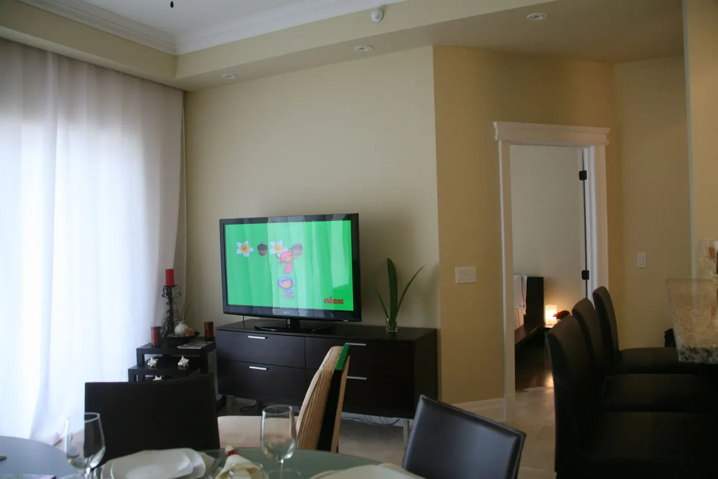 Living area with TV, dining table, and doorway to a bedroom in the penthouse at The Atrium Resort.