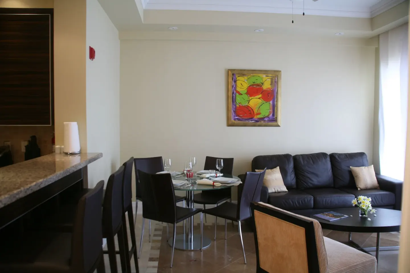 Living and dining area with sofa, round table, and breakfast bar in the penthouse at The Atrium Resort.