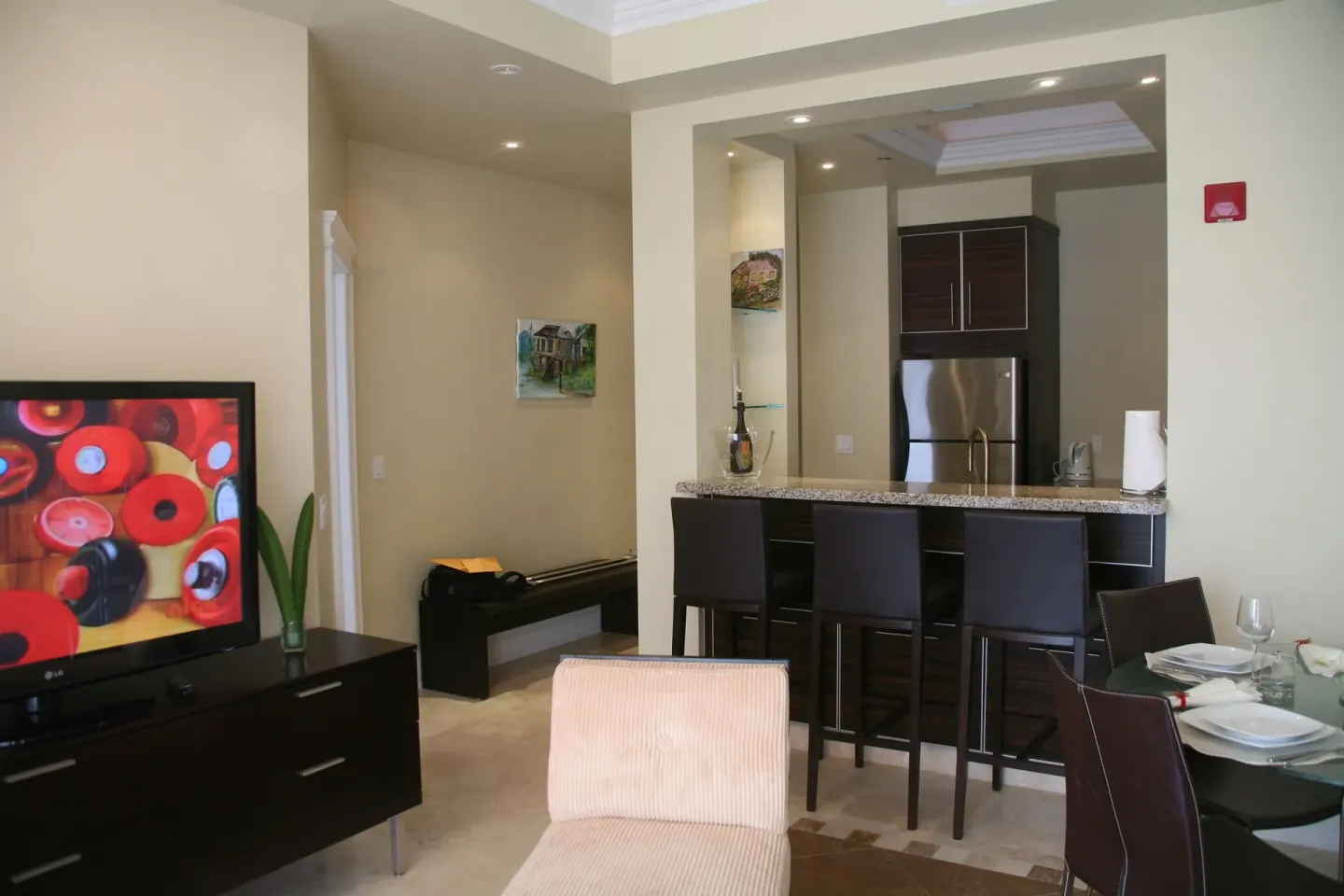 Open living area with TV, armchair, dining table, and kitchen bar in the penthouse at The Atrium Resort.