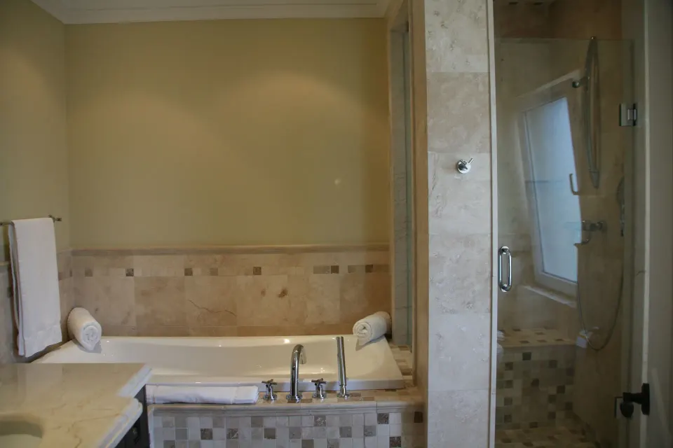 Bathroom with bathtub and glass shower in a two-bedroom condo at The Atrium Resort.