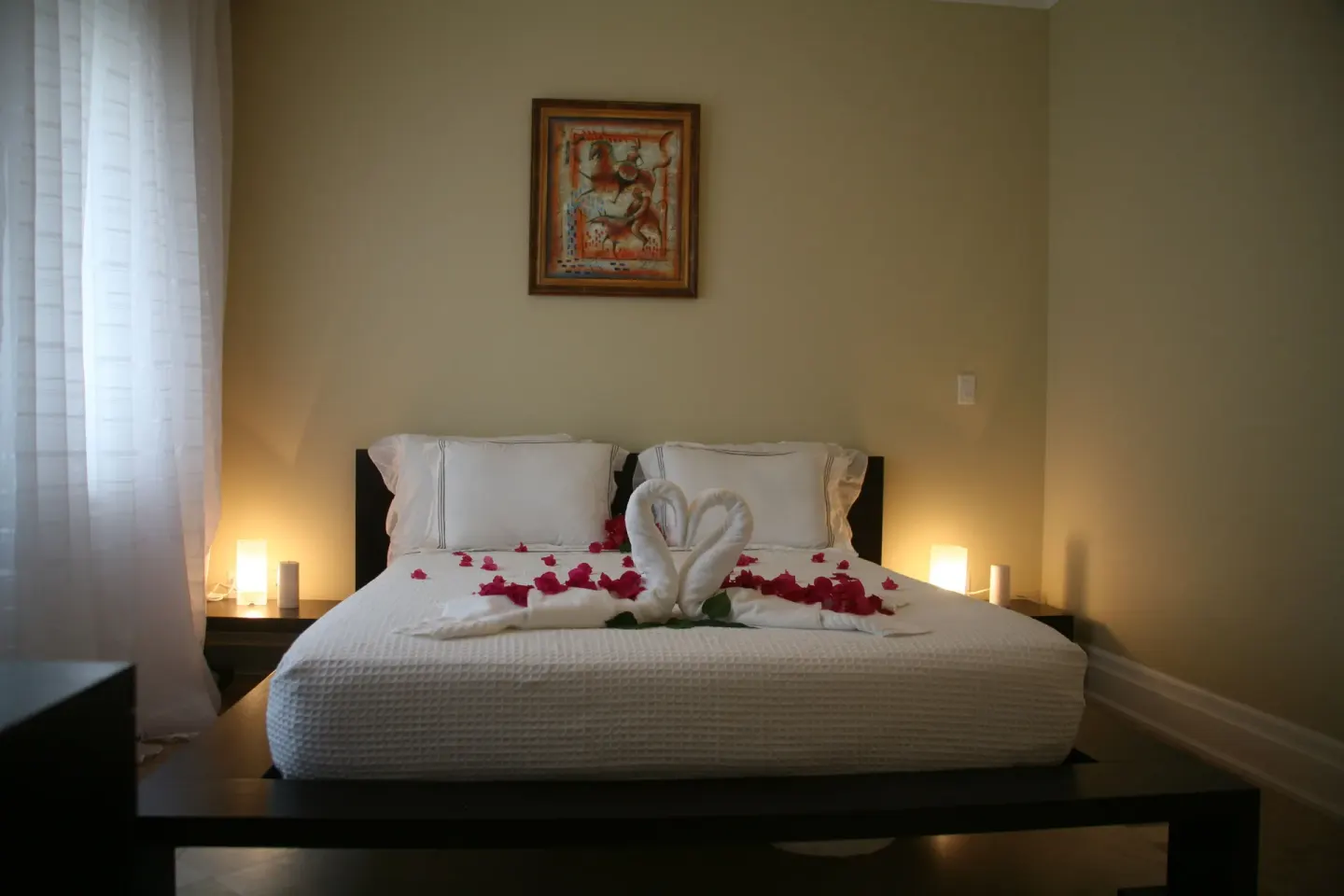 Two-bedroom condo bed with swan towels and rose petals at The Atrium Resort.