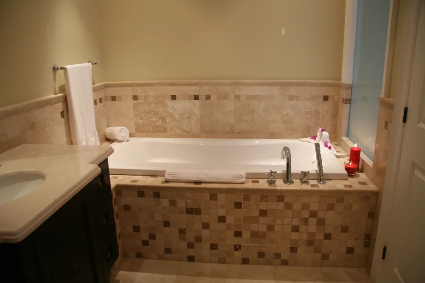 One-bedroom condo bathroom soaking tub with tile surround and candles at The Atrium Resort.