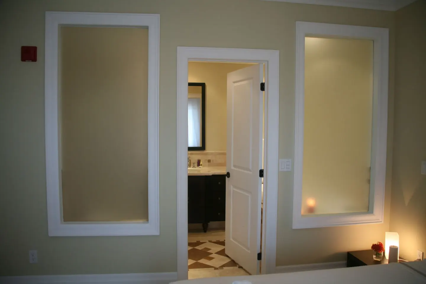 One-bedroom condo bedroom wall with bathroom doorway and bedside lamp at The Atrium Resort.