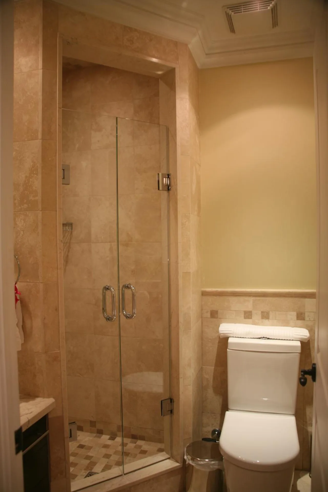Studio bathroom with glass shower, toilet, and tiled walls at The Atrium Resort.