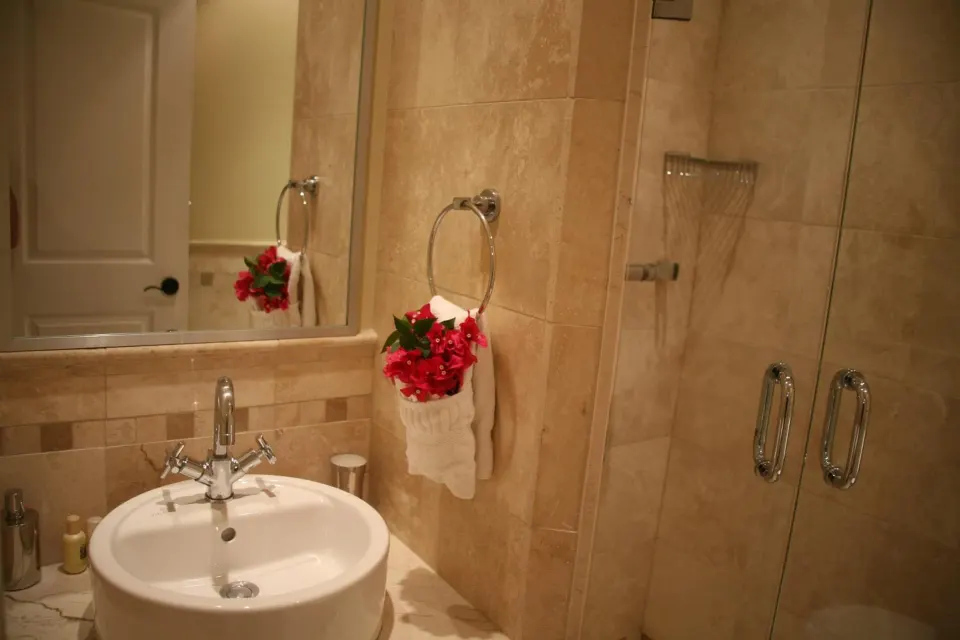 Studio bathroom sink and glass shower with beige tile at The Atrium Resort.