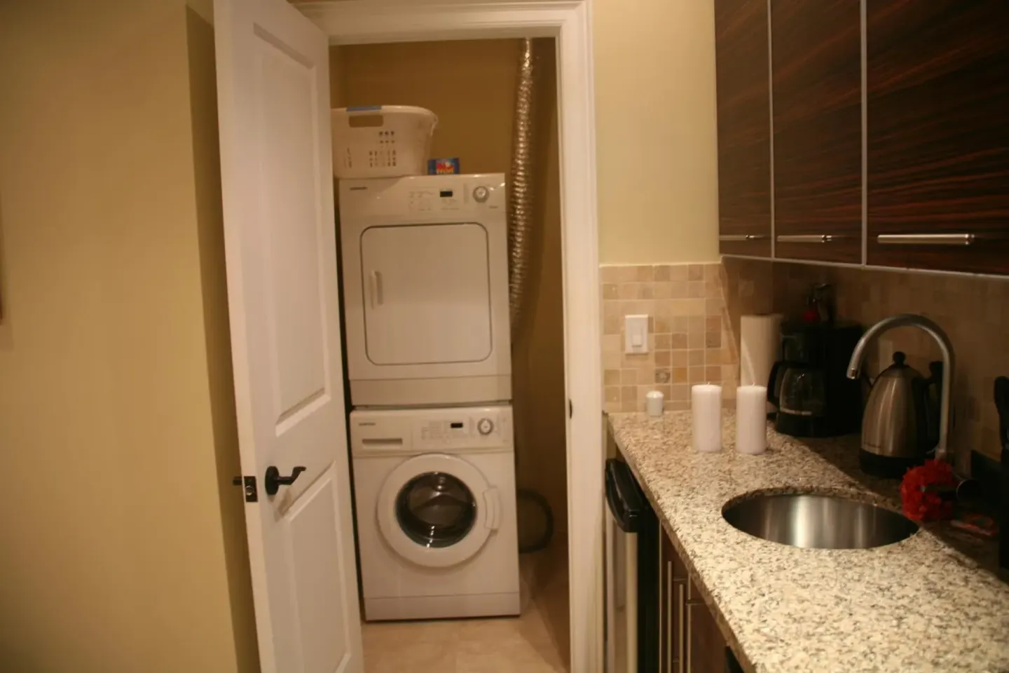 Studio kitchenette with sink and stacked laundry machines at The Atrium Resort.