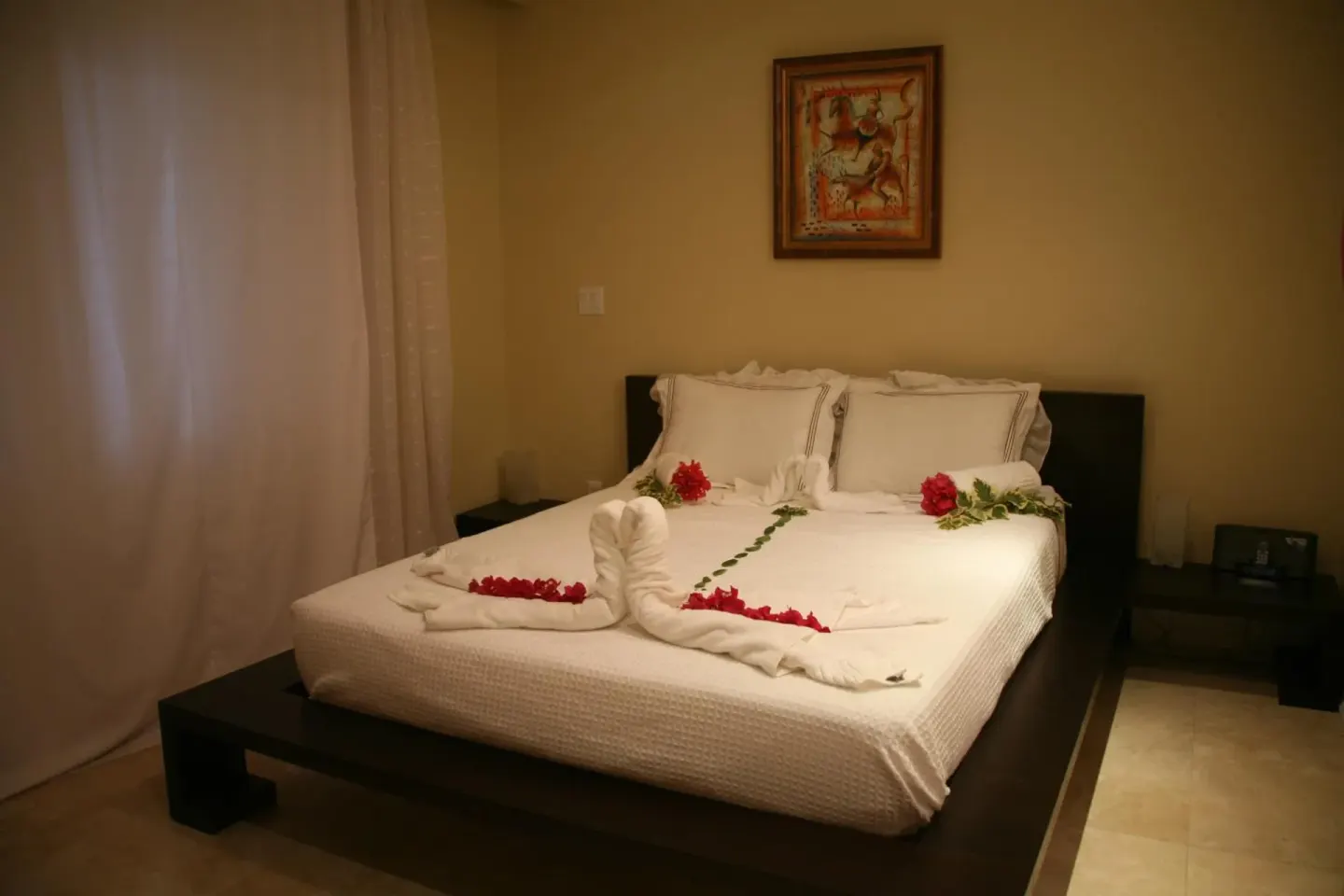 Studio king bed with white linens and floral towel decor at The Atrium Resort.