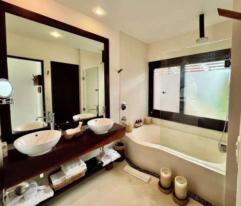 Bright bathroom with overhead shower, tub and double sink at The Beach Tulum